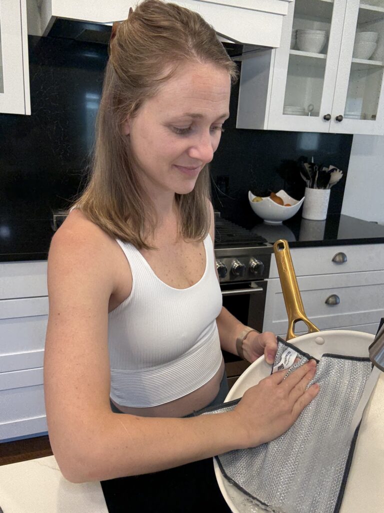 Woman cleaning a non-stick pan with Severn Dish Cloth dual-sided microfiber and mesh kitchen cleaning cloth