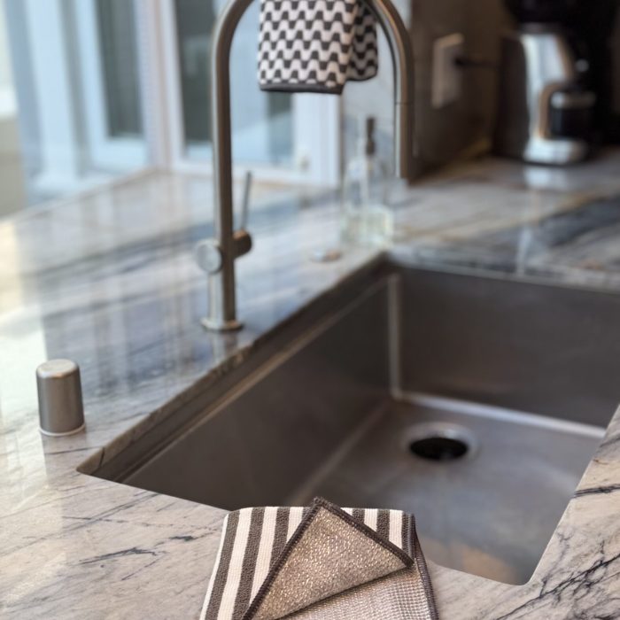 Severn Dish Cloth folded beside a kitchen sink, showing dual-sided microfiber and non-scratch scrubbing surface in a modern kitchen